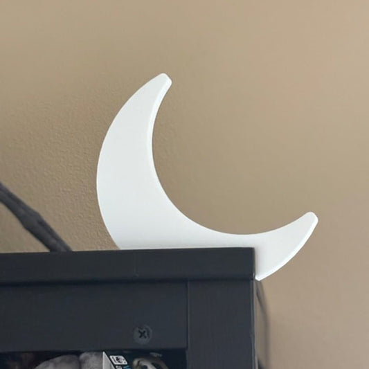 A crescent moon-shaped door topper in dazzling starlight white, shown mounted above a door frame against a white background.