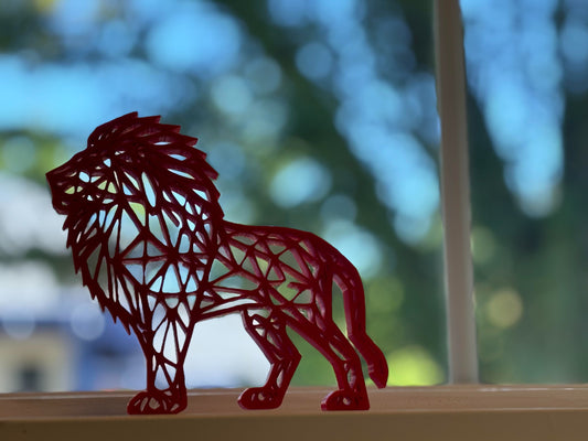 A vibrant ruby red geometric lion figure with a modern and angular design, strikingly displayed on a white surface, commanding attention and admiration.