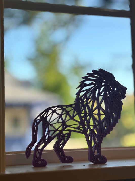 A vibrant magenta colored geometric lion sculpture displayed on a white surface, making a striking and unique decorative piece or gift.